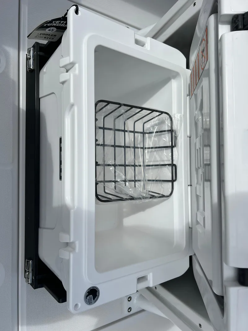 Slide: The Image of Open storage compartment on 2025 Blackfin 272 CC boat, featuring a wire basket. - 47