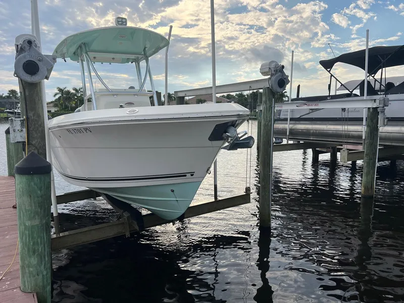 Slide: The Image of 2015 Cobia 237 Center Console boat docked on lift under cloudy sky. - 3