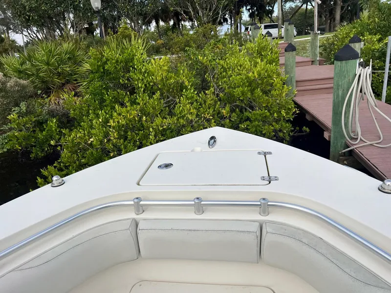 Slide: The Image of 2015 Cobia 237 Center Console boat docked near lush greenery. - 5