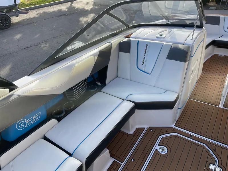 Slide: The Image of 2015 Nautique Super Air G23 boat interior with white seating and teak flooring. - 10