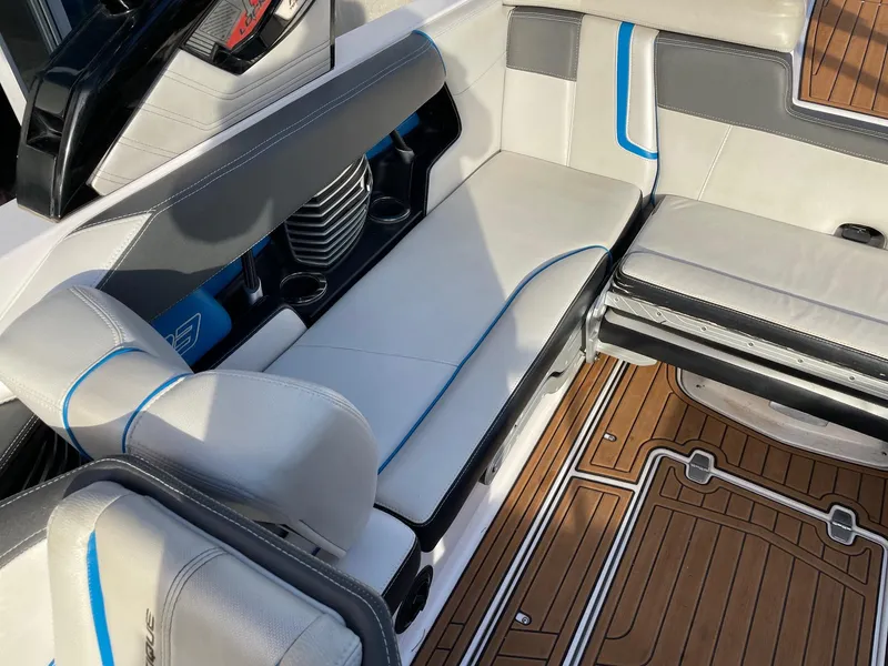 Slide: The Image of 2015 Nautique Super Air G23 interior with white and gray seating, blue accents, and teak flooring. - 7