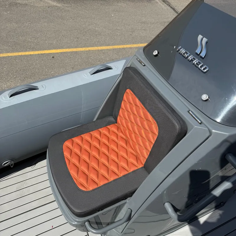 Slide: The Image of 2025 Highfield Sport 520 boat seat with orange quilted cushion and gray console. - 6