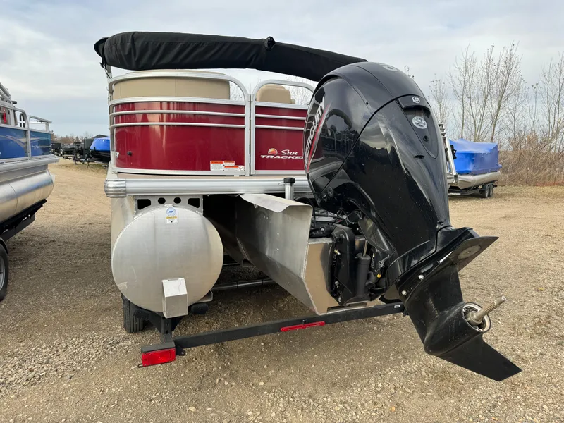 Slide: The Image of 2022 Sun Tracker Party Barge 22 XP3 with outboard motor, parked on gravel. - 5