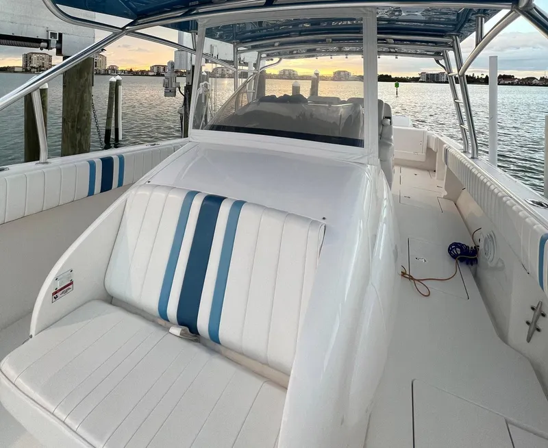 Slide: The Image of 2016 Intrepid 400 Center Console boat with white and blue seating, docked at sunset. - 12