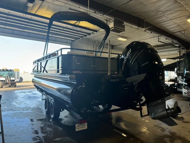 Slide: The Image of 2021 Regency 250 DL3 pontoon boat in a garage with Mercury outboard motor. - 3