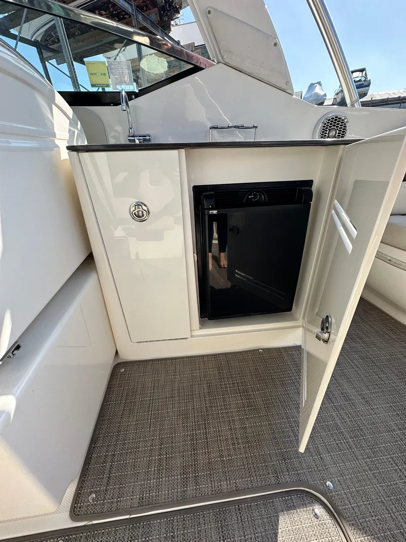 Slide: The Image of 2013 Sea Ray 300 SLX boat interior with open cabinet and mini fridge. - 15
