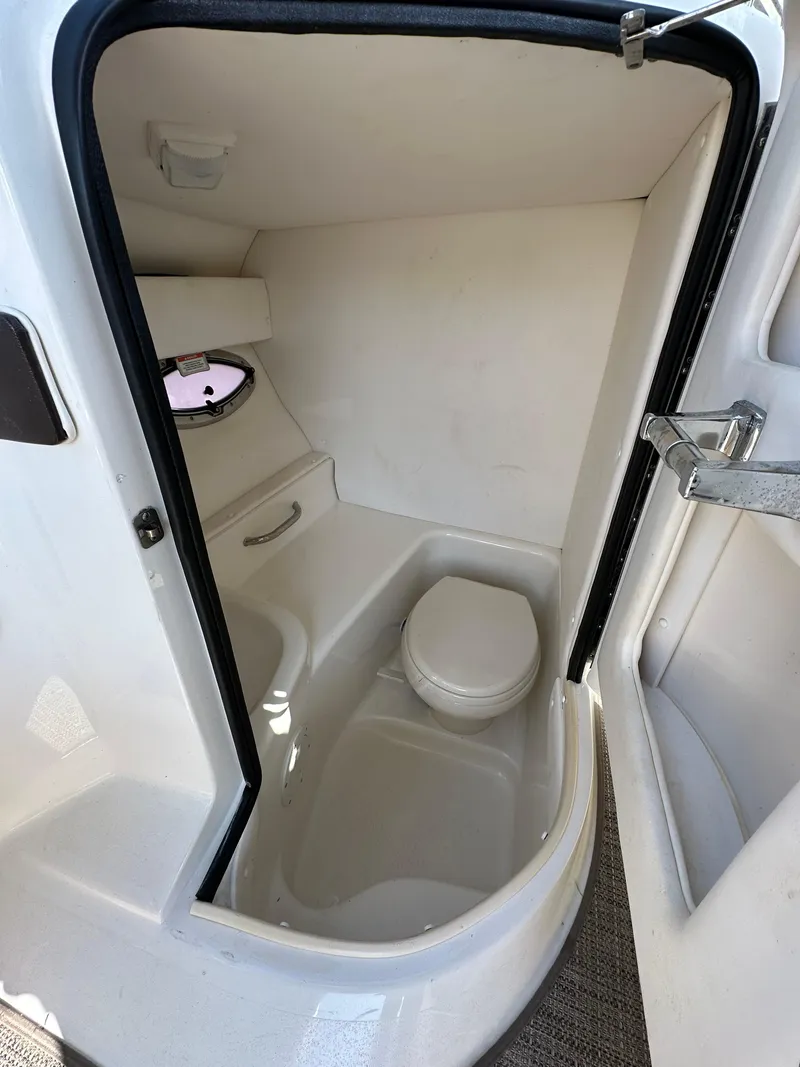 Slide: The Image of 2013 Sea Ray 300 SLX boat interior bathroom with compact toilet and small window. - 18