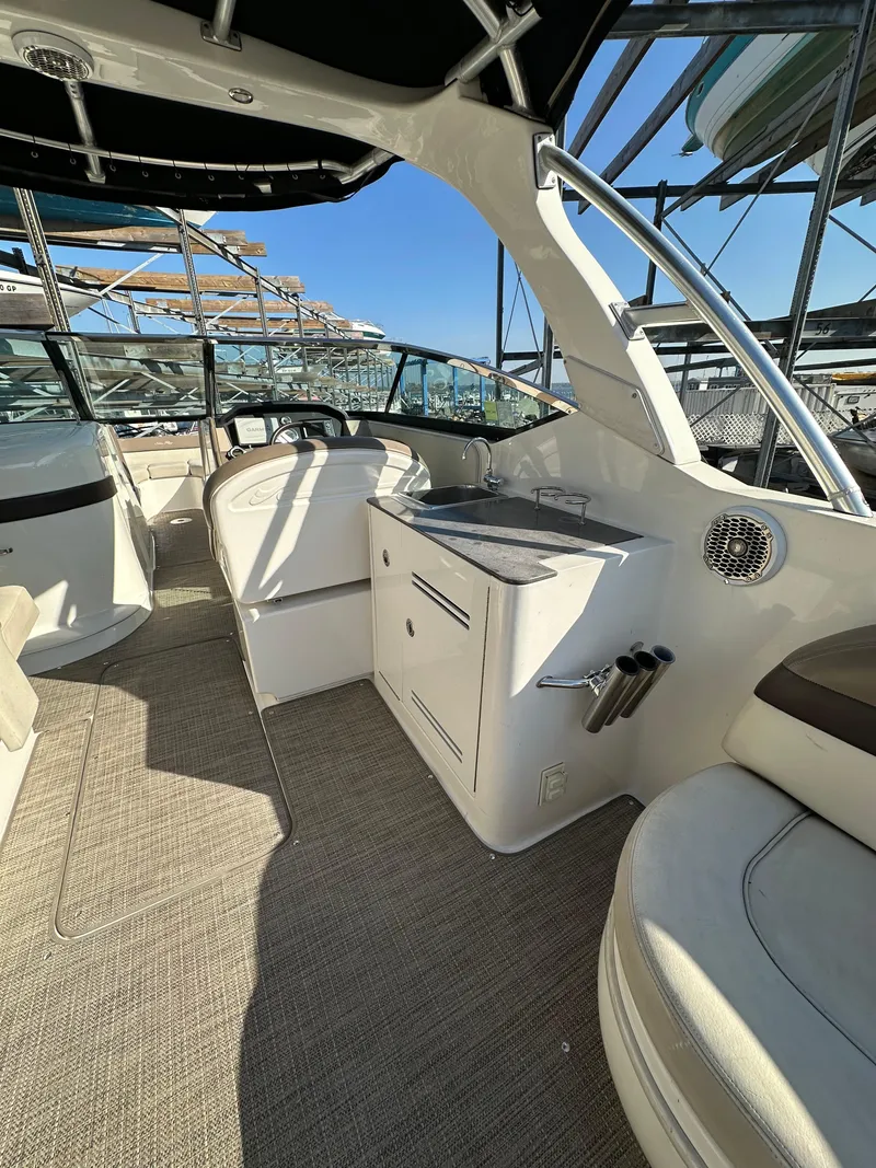 Slide: The Image of 2013 Sea Ray 300 SLX boat interior with seating and helm, under clear blue sky. - 2