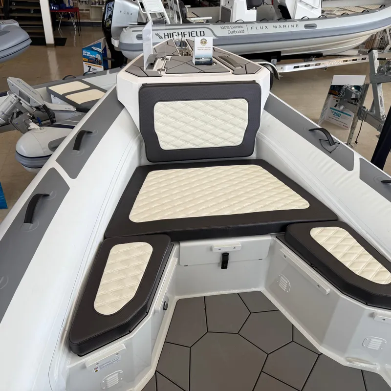 Slide: The Image of 2025 Highfield Sport 700 boat interior with cushioned seating in a showroom. - 14