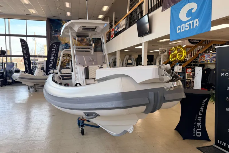 Slide: The Image of 2025 Highfield Sport 700 boat displayed in showroom with promotional banners. - 32