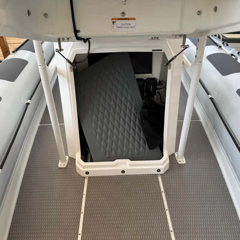 Slide: The Image of 2025 Highfield Patrol 860 boat storage compartment with open hatch and cushion inside. - 23