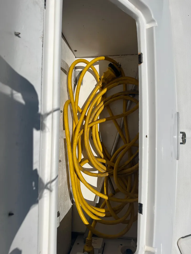 Slide: The Image of Yellow power cord stored in a compartment of a 2005 Sea Ray 280 Sundancer boat. - 11
