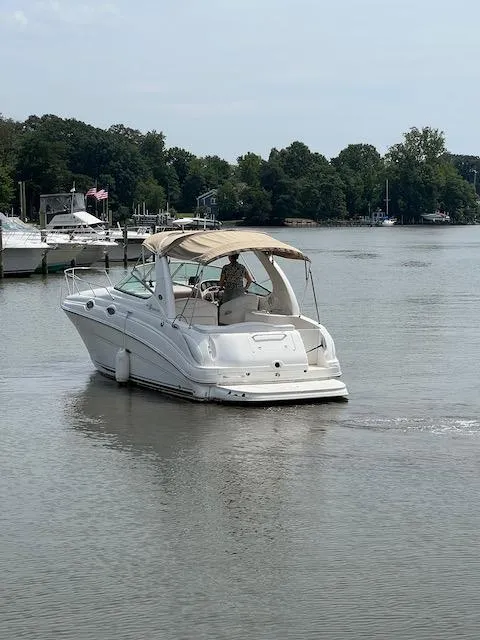 Slide: The Image of 2005 Sea Ray 280 Sundancer cruising on a calm river near a marina. - 2