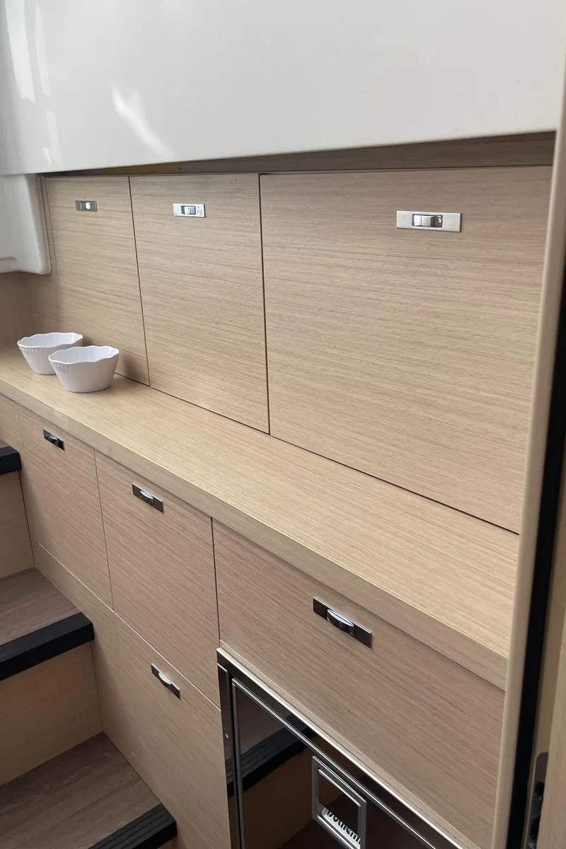 Slide: The Image of 2025 Jeanneau DB/37 OB interior cabinetry with modern wood finish. - 19