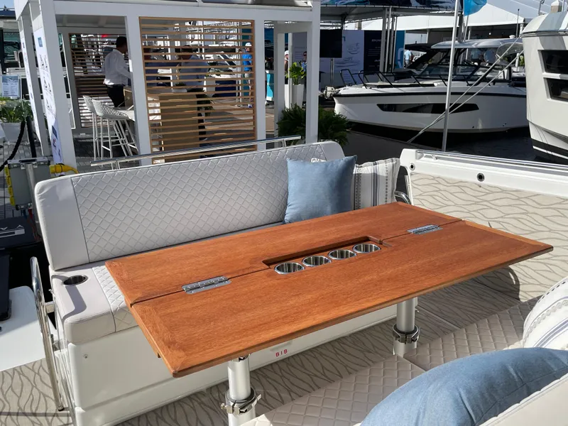 Slide: The Image of 2025 Jeanneau DB/37 OB boat interior with wooden table and cushioned seating. - 2