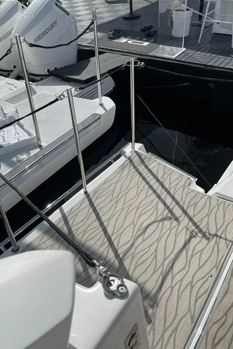 Slide: The Image of 2025 Jeanneau DB/37 OB boat deck with patterned flooring and docked Mercury engines. - 7