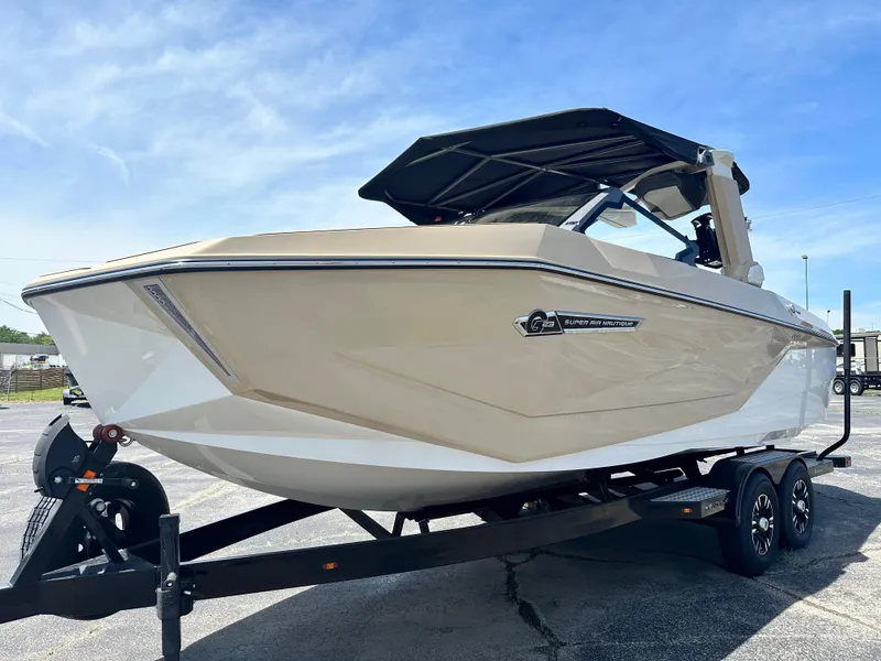 Slide: The Image of 2025 Nautique Super Air Nautique G23 boat on trailer, under clear blue sky. - 1