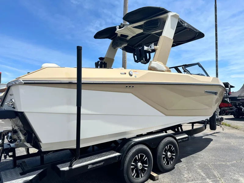 Slide: The Image of 2025 Nautique Super Air Nautique G23 boat on trailer, beige and white design, sunny day. - 11