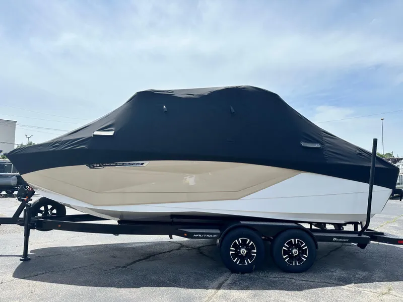 Slide: The Image of 2025 Nautique Super Air Nautique G23 boat covered on trailer, side view. - 12