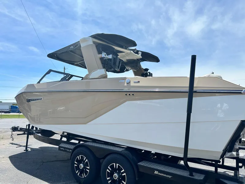 Slide: The Image of 2025 Nautique Super Air Nautique G23 boat on trailer, side view under clear sky. - 2