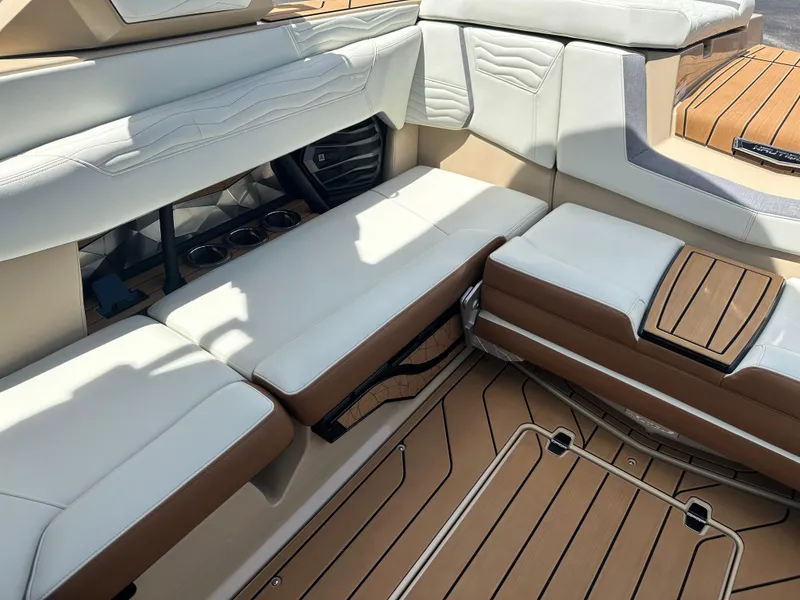 Slide: The Image of 2025 Nautique Super Air Nautique G23 interior with tan and white seating, teak flooring. - 20