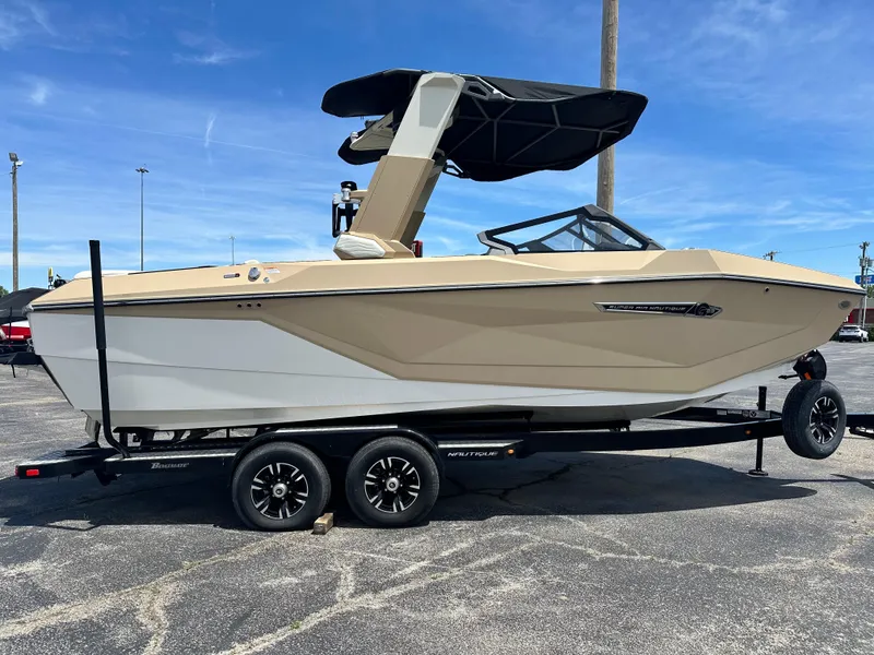 Slide: The Image of 2025 Nautique Super Air Nautique G23 boat on trailer, beige and white design, parked outdoors. - 9