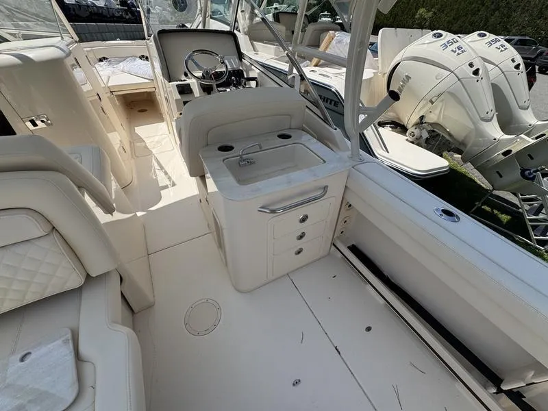 Slide: The Image of 2025 Grady-White Freedom 275 boat interior with helm, sink, and twin outboard engines. - 10