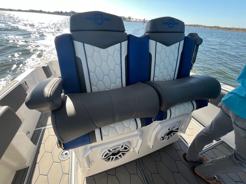 Slide: The Image of 2022 Fountain 34 SC boat seats with blue and white upholstery on a sunny day. - 22
