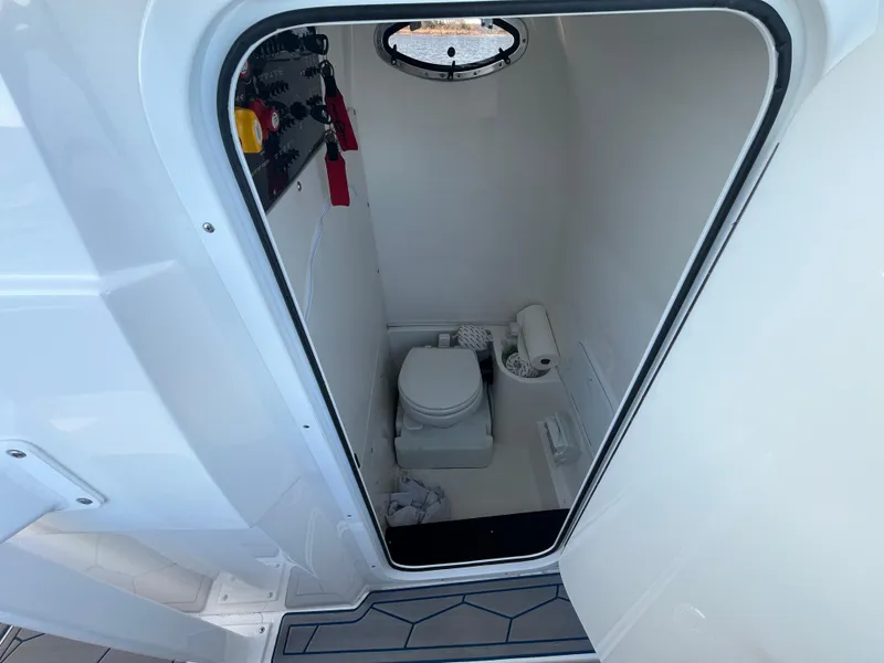 Slide: The Image of 2022 Fountain 34 SC boat interior bathroom with compact toilet and porthole. - 30