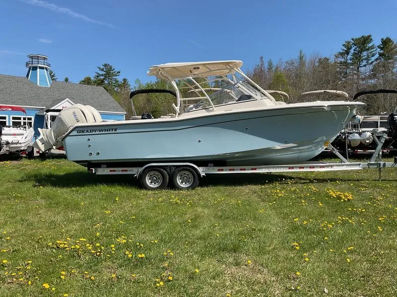 The Image of 2025 Grady-White Freedom 275 boat on trailer, parked on grass under clear blue sky. - 0