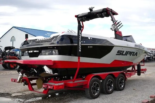 Slide: The Image of 2021 Supra SE 450 boat on trailer, black and red design, parked outdoors. - 5