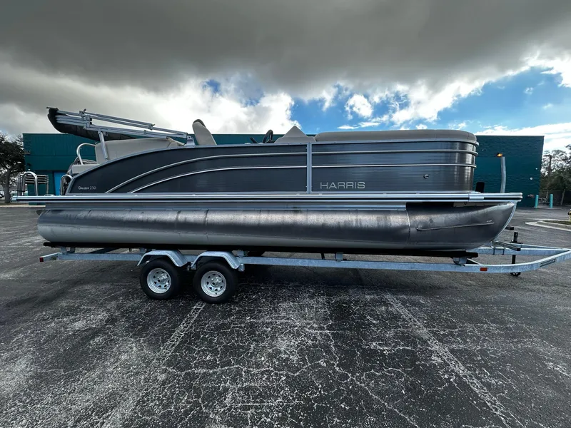 The Image of 2023 Harris Cruiser 230 pontoon boat on trailer under cloudy sky. - 1
