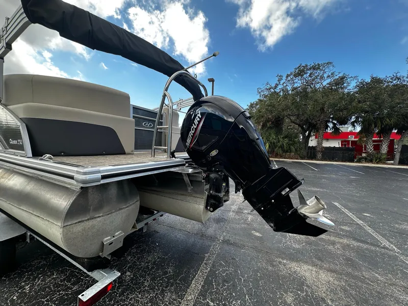 Slide: The Image of 2023 Harris Cruiser 230 pontoon boat with Mercury outboard motor in parking lot. - 4