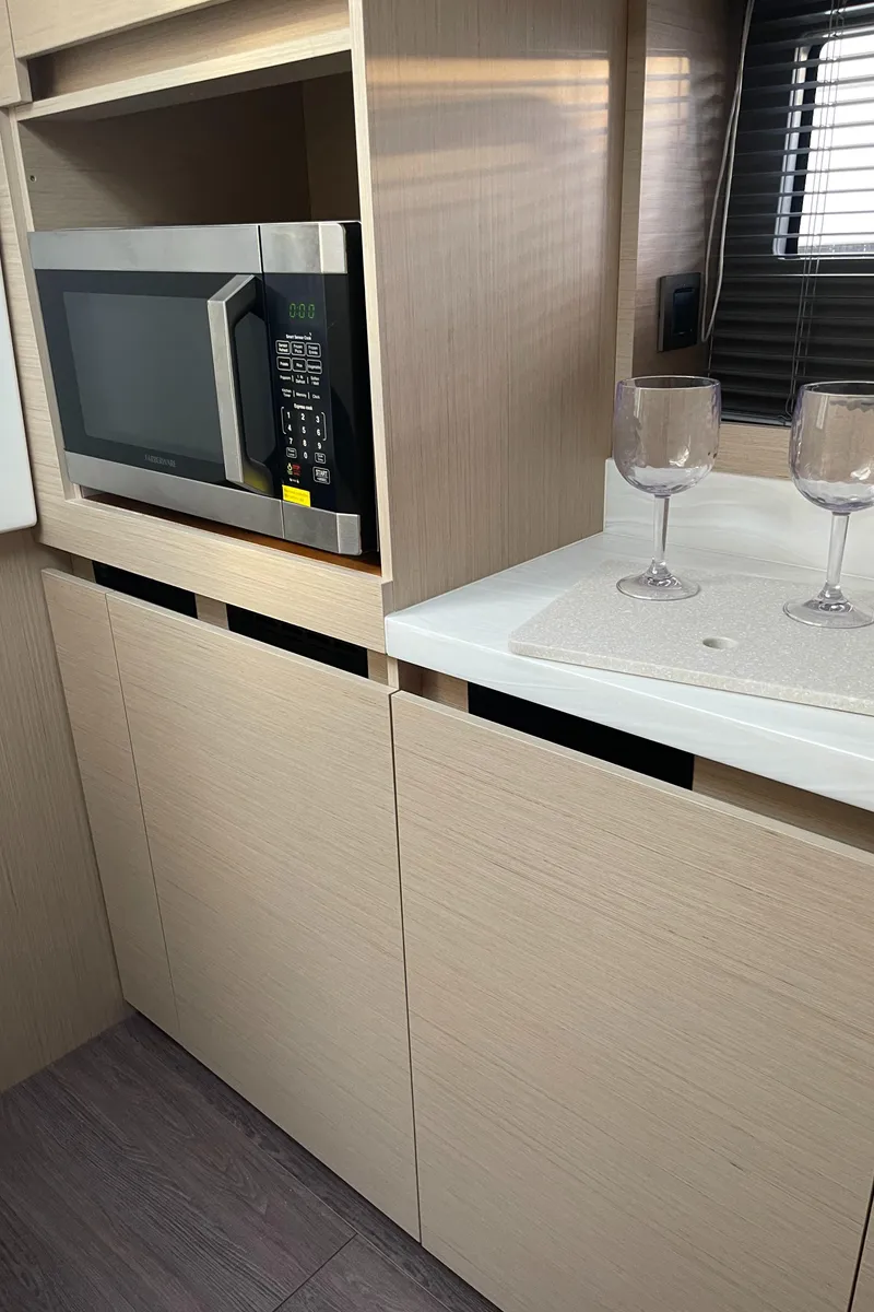 Slide: The Image of Modern kitchen area in 2025 Jeanneau DB/43 OB yacht with microwave and wine glasses. - 24
