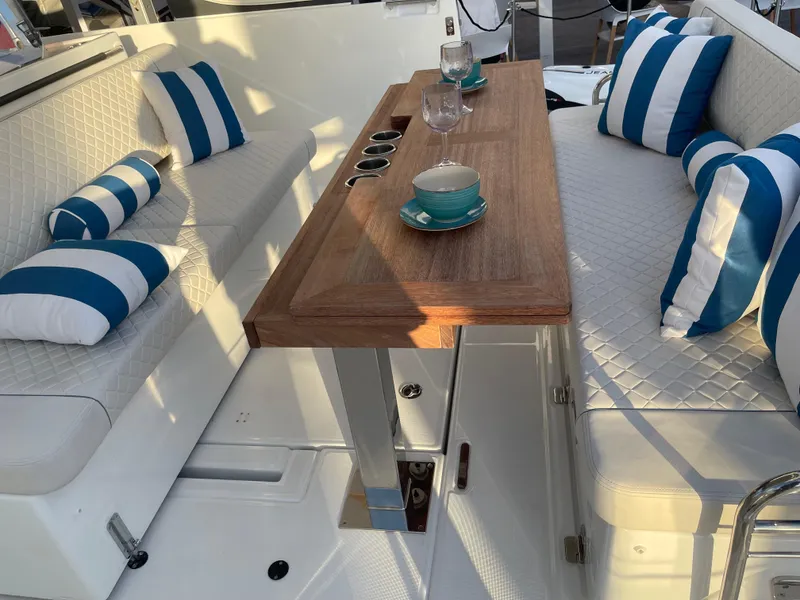 Slide: The Image of 2025 Jeanneau DB/43 OB boat interior with striped cushions and wooden table. - 2