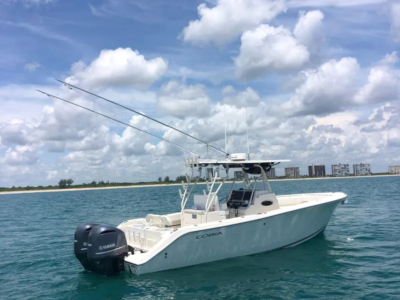 Slide: The Image of 2014 Cobia 296 Center Console boat on calm ocean waters under a cloudy sky. - 10