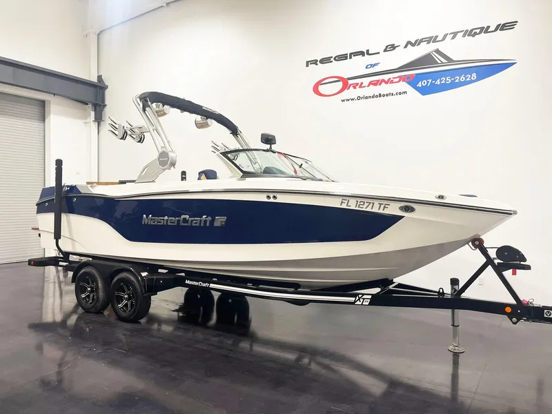 Slide: The Image of 2022 MasterCraft NXT24 boat with tan and blue interior, displayed indoors. - 3