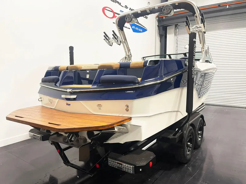 Slide: The Image of 2022 MasterCraft NXT24 boat, blue and white, rear view with wooden swim platform. - 5
