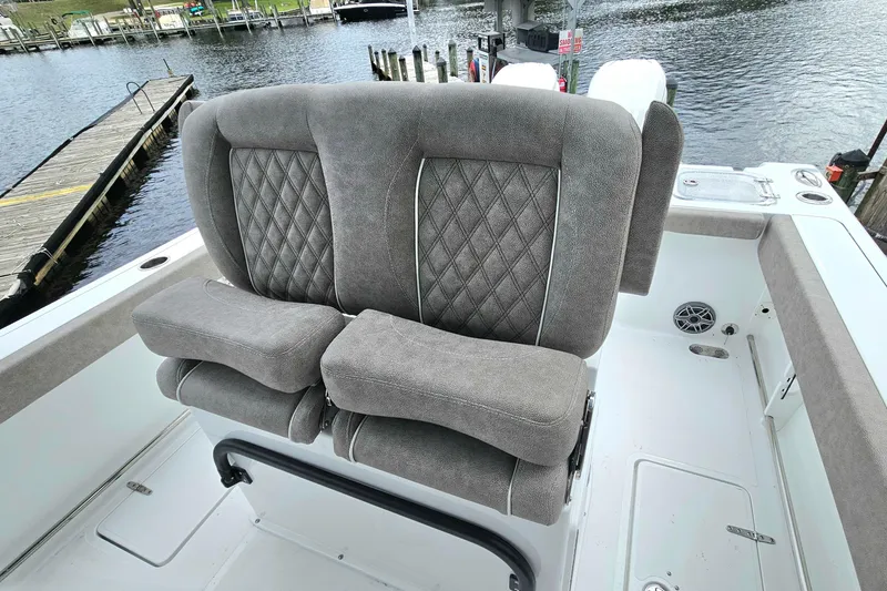 Slide: The Image of 2026 Sea Hunt Gamefish 25 boat with plush, diamond-stitched seating near a dock. - 15