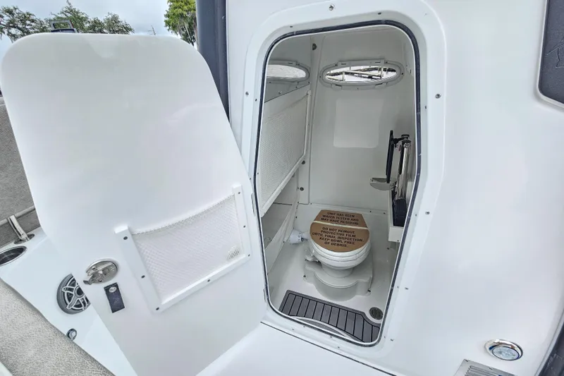 Slide: The Image of 2026 Sea Hunt Gamefish 25 boat interior with open door revealing compact marine toilet. - 17