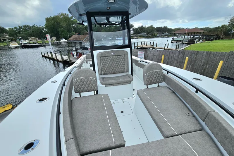 Slide: The Image of 2026 Sea Hunt Gamefish 25 boat with spacious seating, docked by a scenic waterfront. - 18