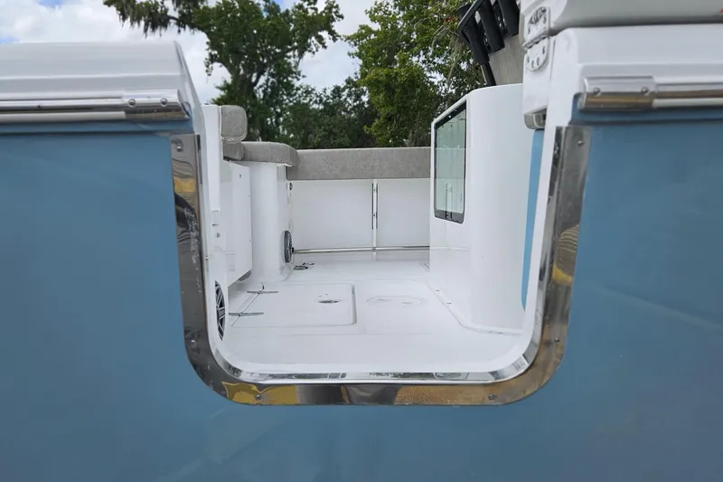 Slide: The Image of 2026 Sea Hunt Gamefish 25 boat interior with open side door, blue exterior, and white deck. - 2