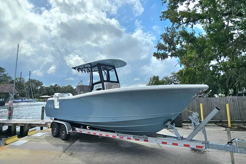 Slide: The Image of 2026 Sea Hunt Gamefish 25 boat on trailer at dockside under cloudy sky. - 4