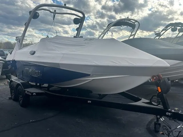 Slide: The Image of 2024 Malibu 20VTX boat covered, parked on trailer under cloudy sky. - 5