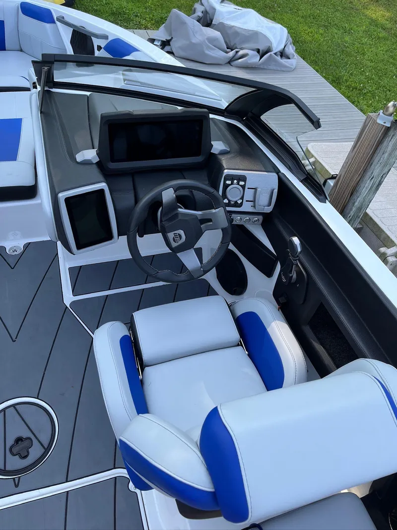 Slide: The Image of 2024 Malibu 20VTX boat interior with modern dashboard and blue-accented seating. - 9