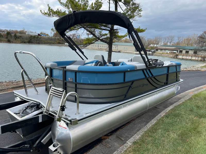 Slide: The Image of 2025 South Bay SS222 RS pontoon boat docked by a scenic lake. - 6