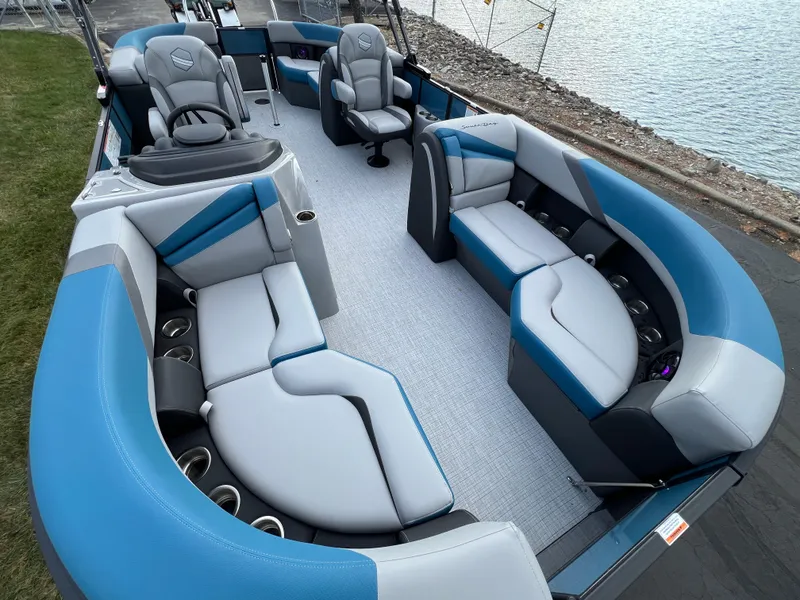 Slide: The Image of 2025 South Bay SS222 RS pontoon boat interior with blue and gray seating by the water. - 7