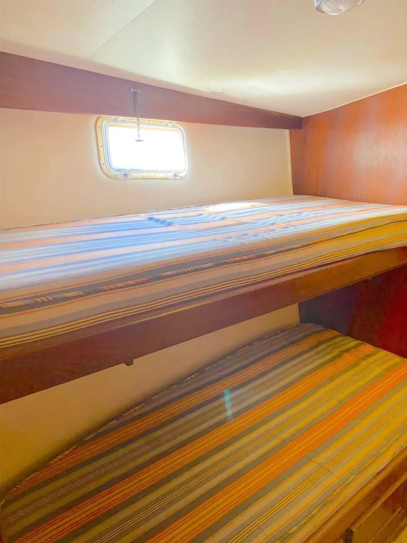 Slide: The Image of 1975 Hatteras 36 Convertible cabin with striped bunk beds and small window. - 17
