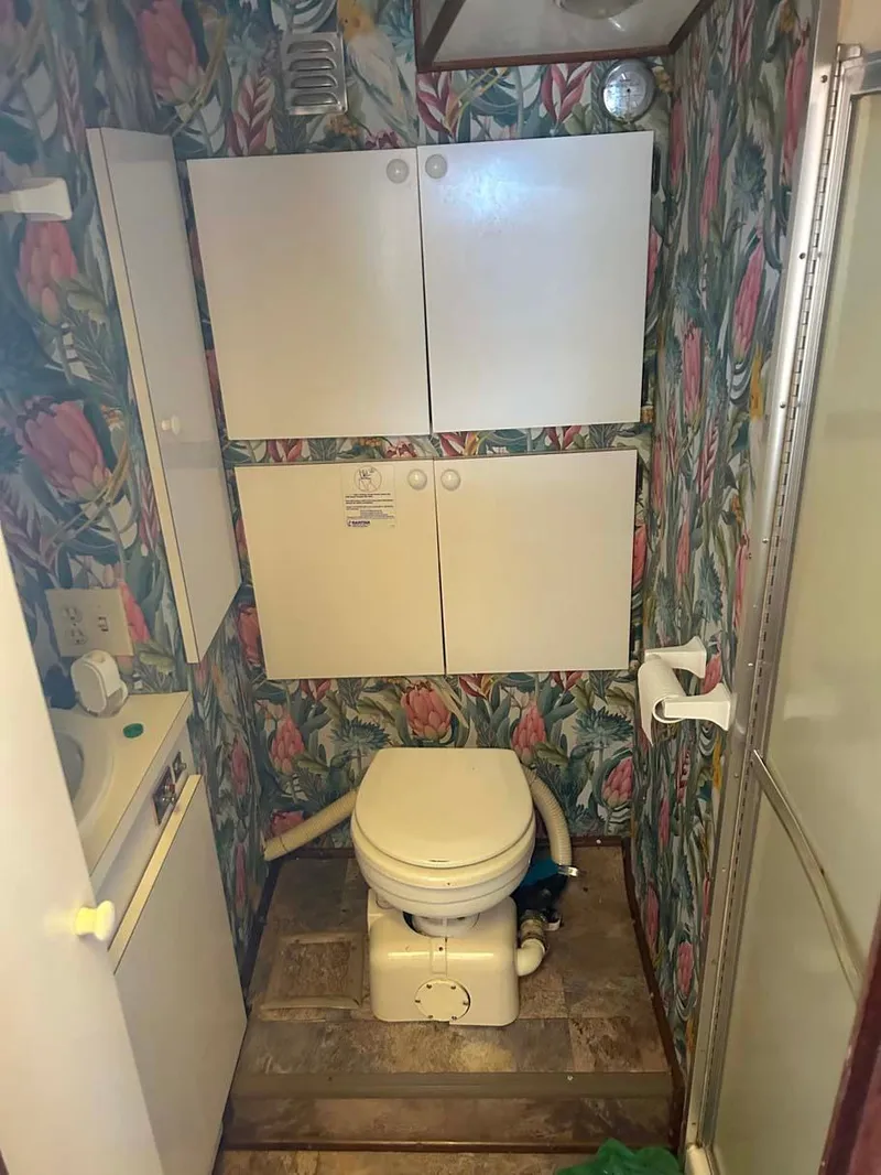 Slide: The Image of 1975 Hatteras 36 Convertible bathroom with floral wallpaper and compact storage cabinets. - 19