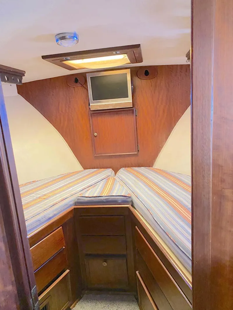 Slide: The Image of 1975 Hatteras 36 Convertible cabin with striped bedding and wood paneling. - 21